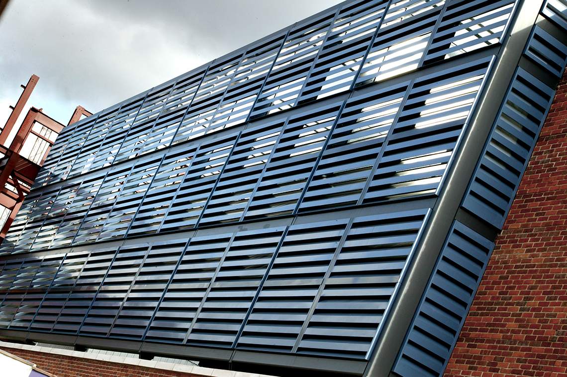 Akustisk fasadbeklädnad (Acoustic Louvers Slimshield™) som minskar buller, monterat vid ett parkeringshus.