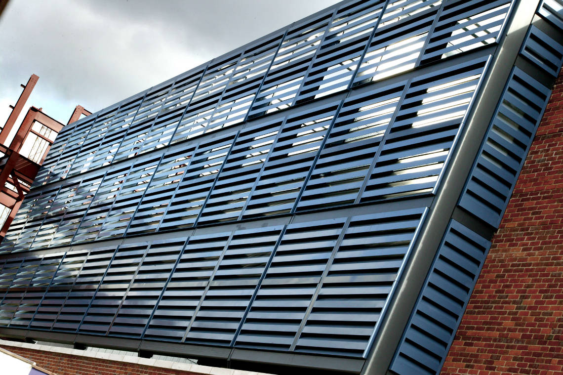 Akustisk fasadbeklädnad (Acoustic Louvers Slimshield™) som minskar buller, monterat vid ett parkeringshus.